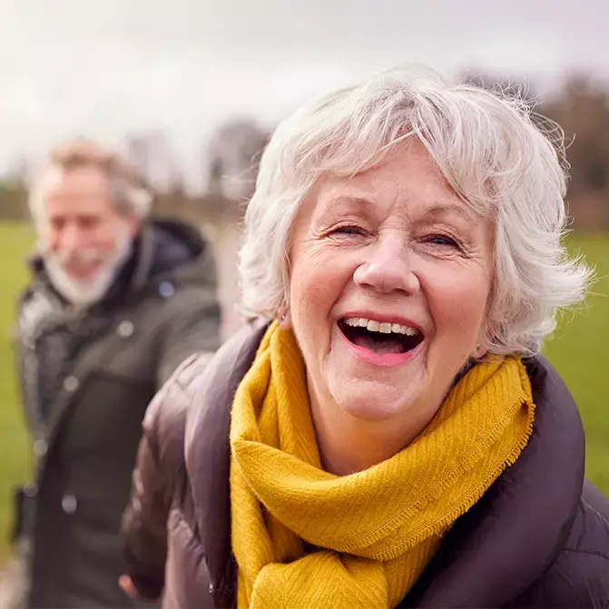 Elderly couple outside in a field laughing