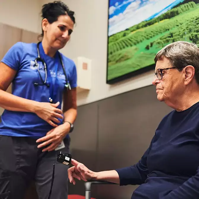 A senior woman checking her heart rate with her doctor.